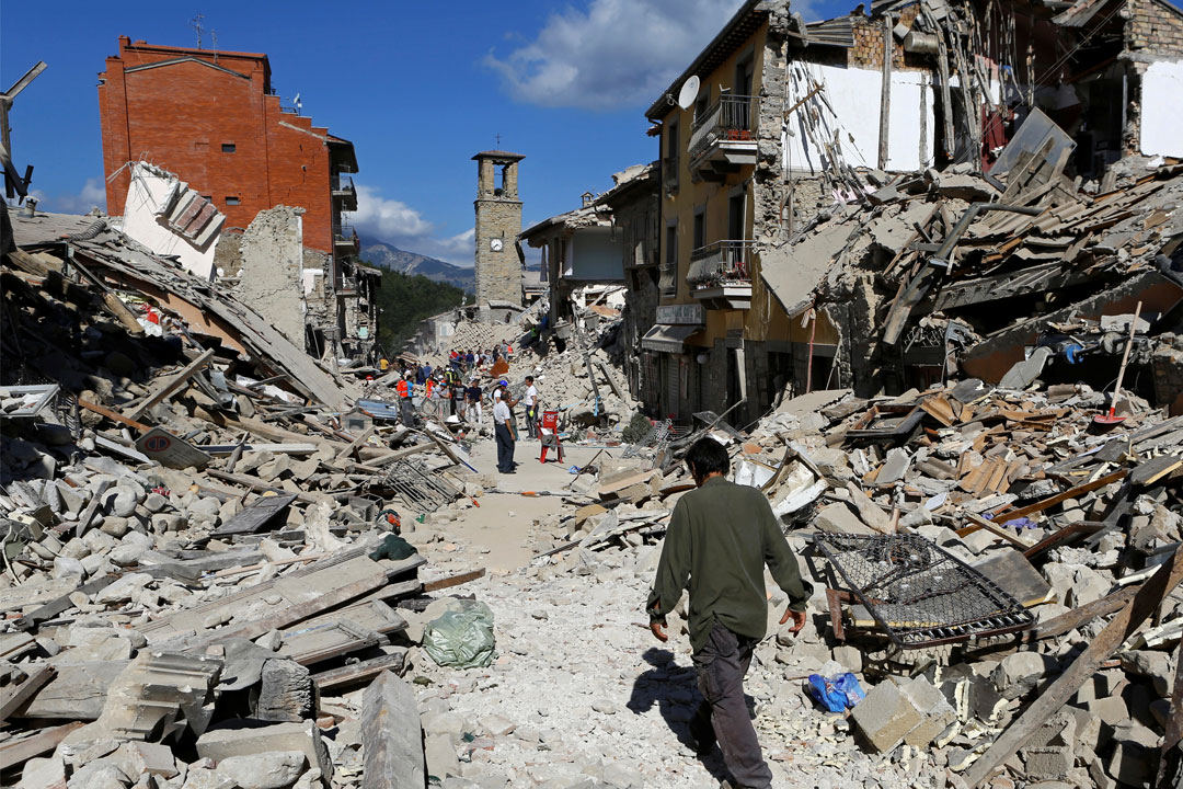 A man walks through rubble between destroyed buildings