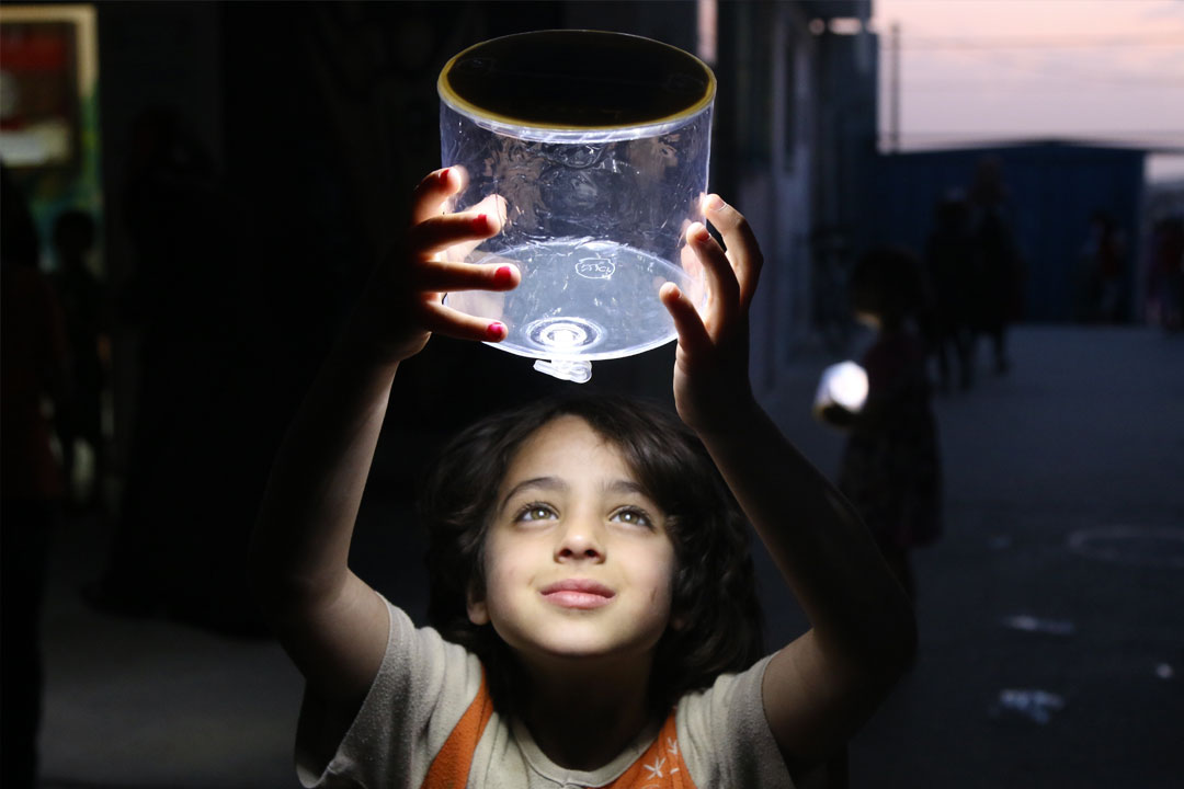 A child smiles while lifting an electric lamp