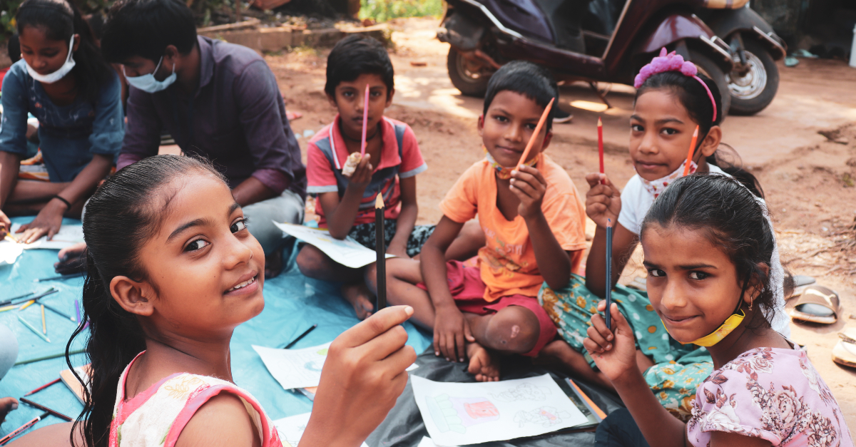Children coloring pictures together, smiling. Nonprofit year-end.